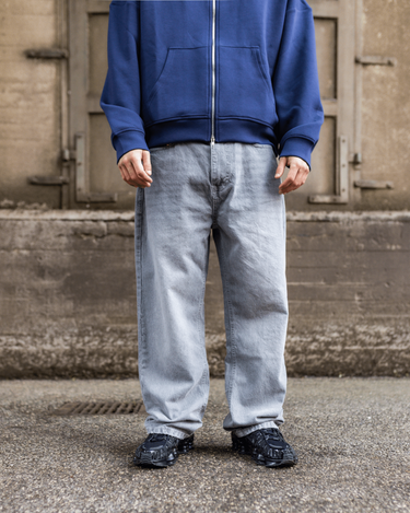 Model i lysegrå Tyler baggy jeans med lav talje og blå hættetrøje.